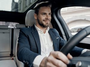 man in business attire driving a car