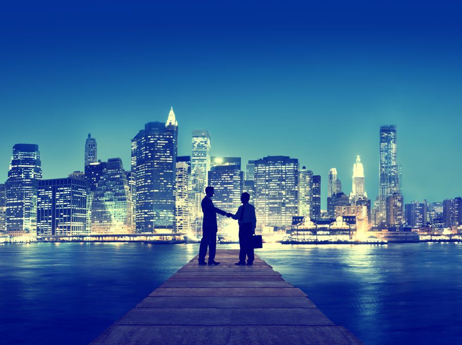 men shaking hands with city skyline behind them
